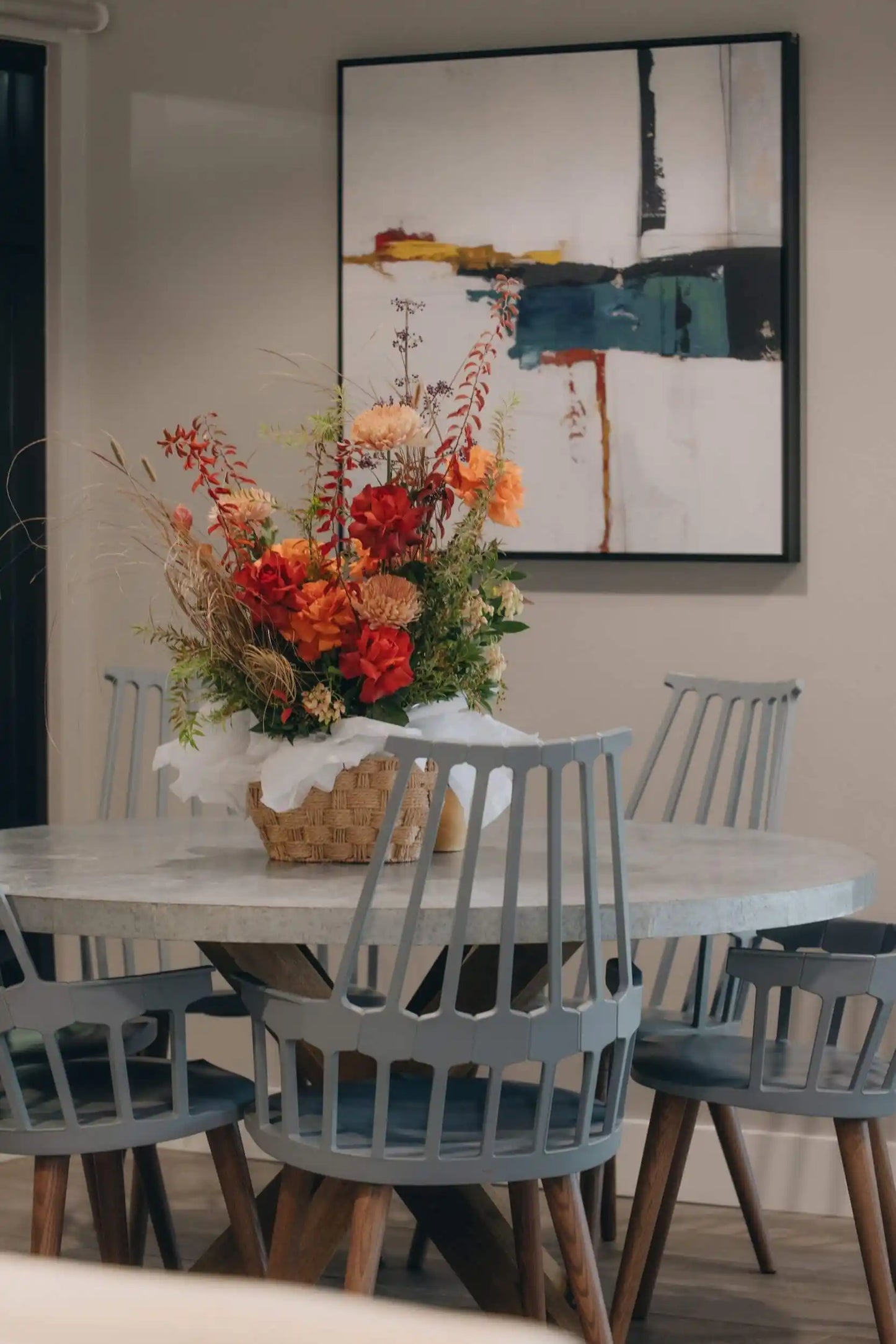 Bright seasonal flower basket with red roses and orange blooms on modern dining table in Portland home