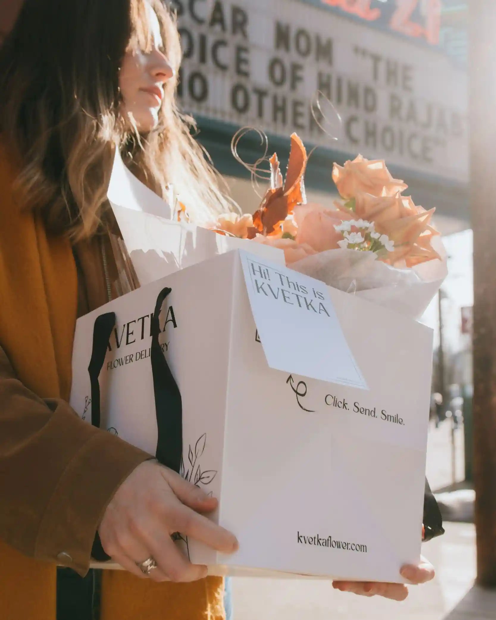 Woman holding Kvetka Flower signature branded gift box with fresh bouquet ready for delivery
