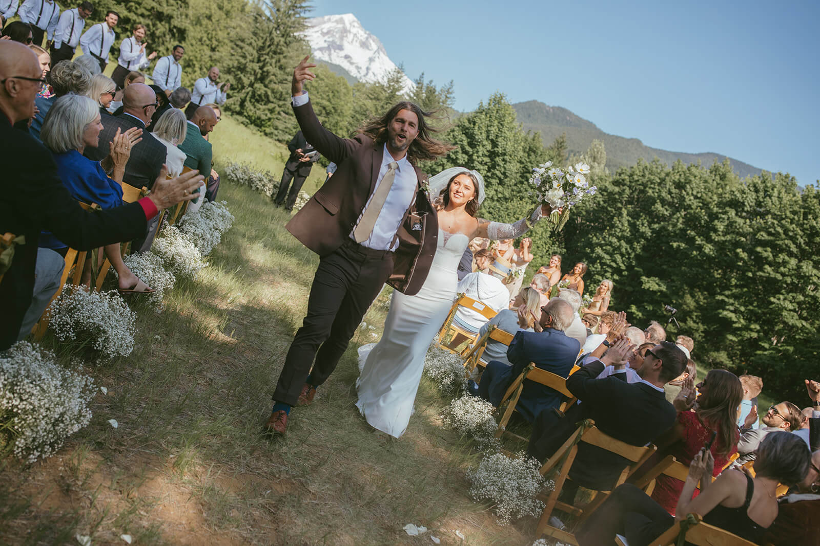 Joyful wedding ceremony exit with bride and groom holding bouquet by Kvetka Flower Portland OR