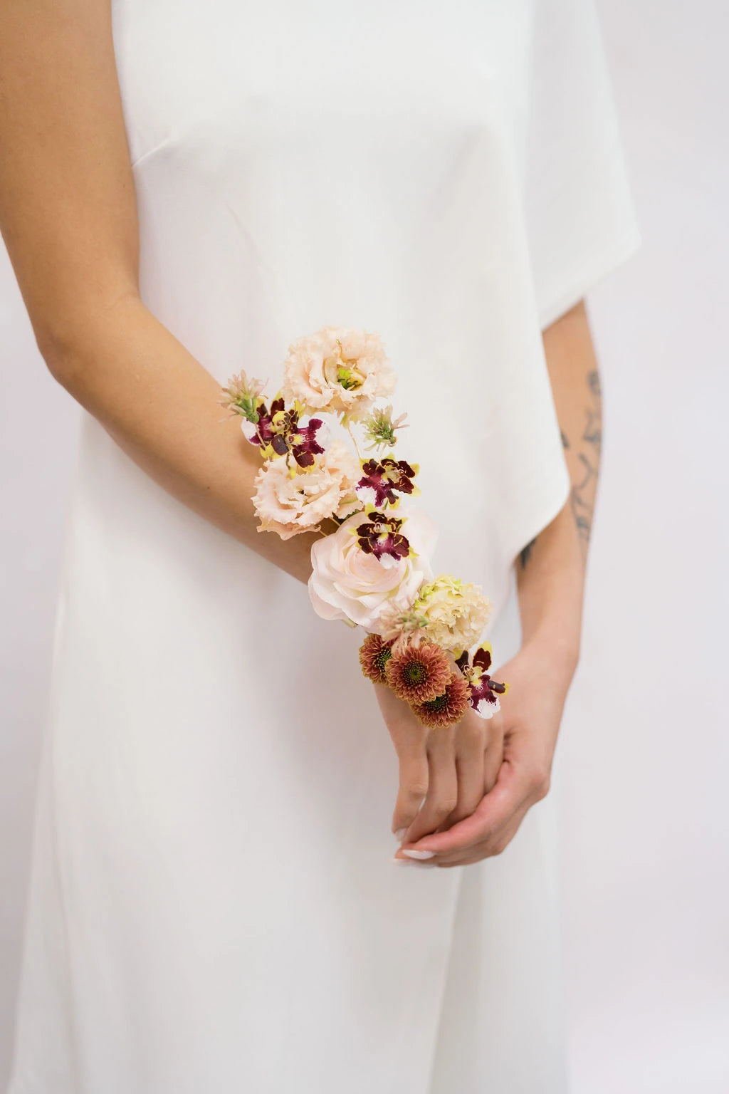 Detail shot of wearable arm corsage with blush carnations and burgundy mini orchids Portland OR